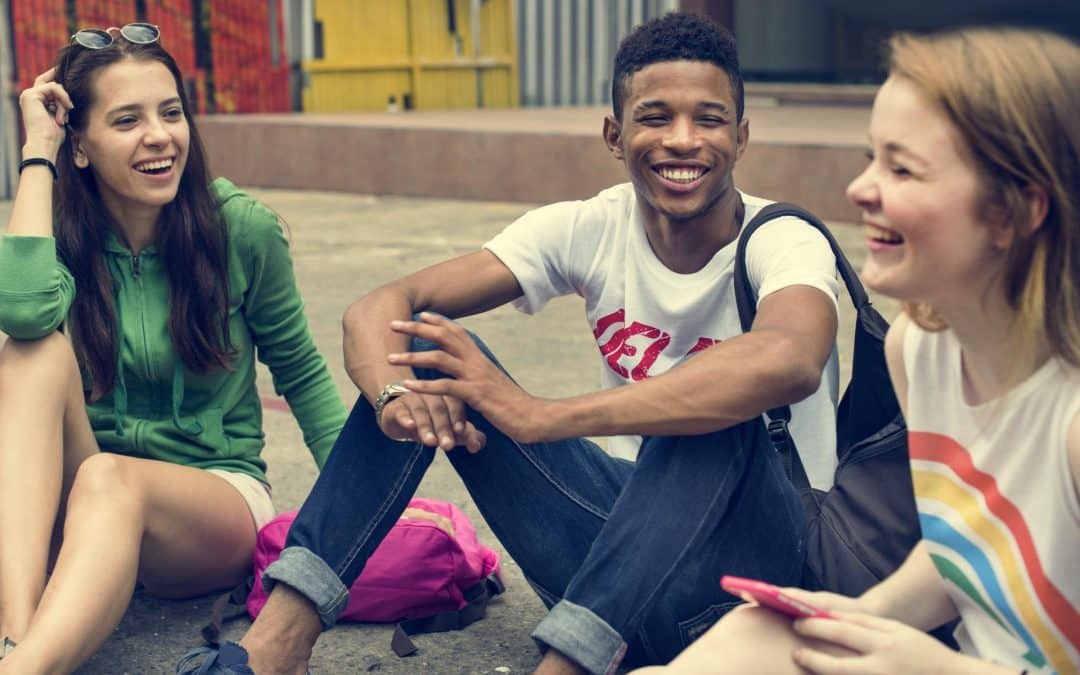 (decorative image) Three young people sitting on the floor smiling and hanging out