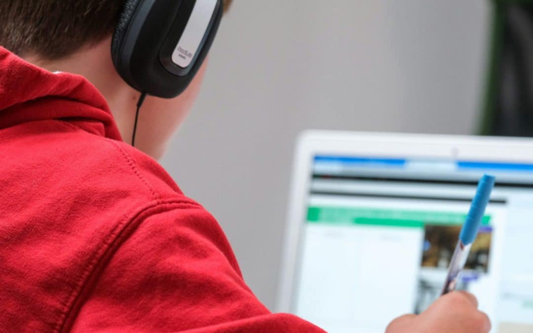 Image of a young person sitting at a computer with headphones on
