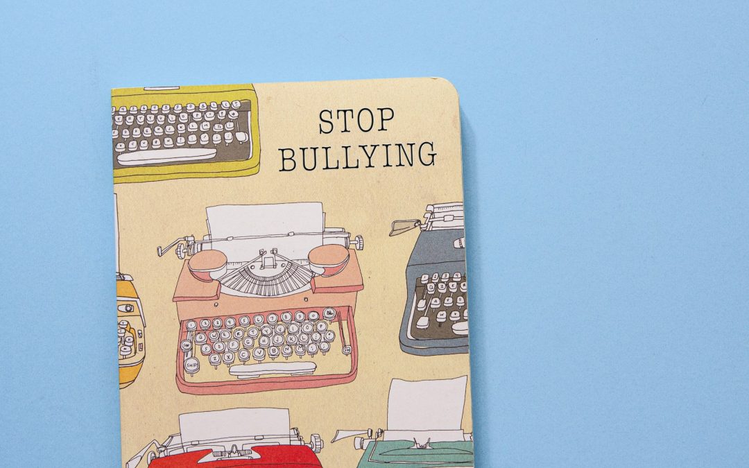 Notebook with stop bullying written on it, against a blue background.